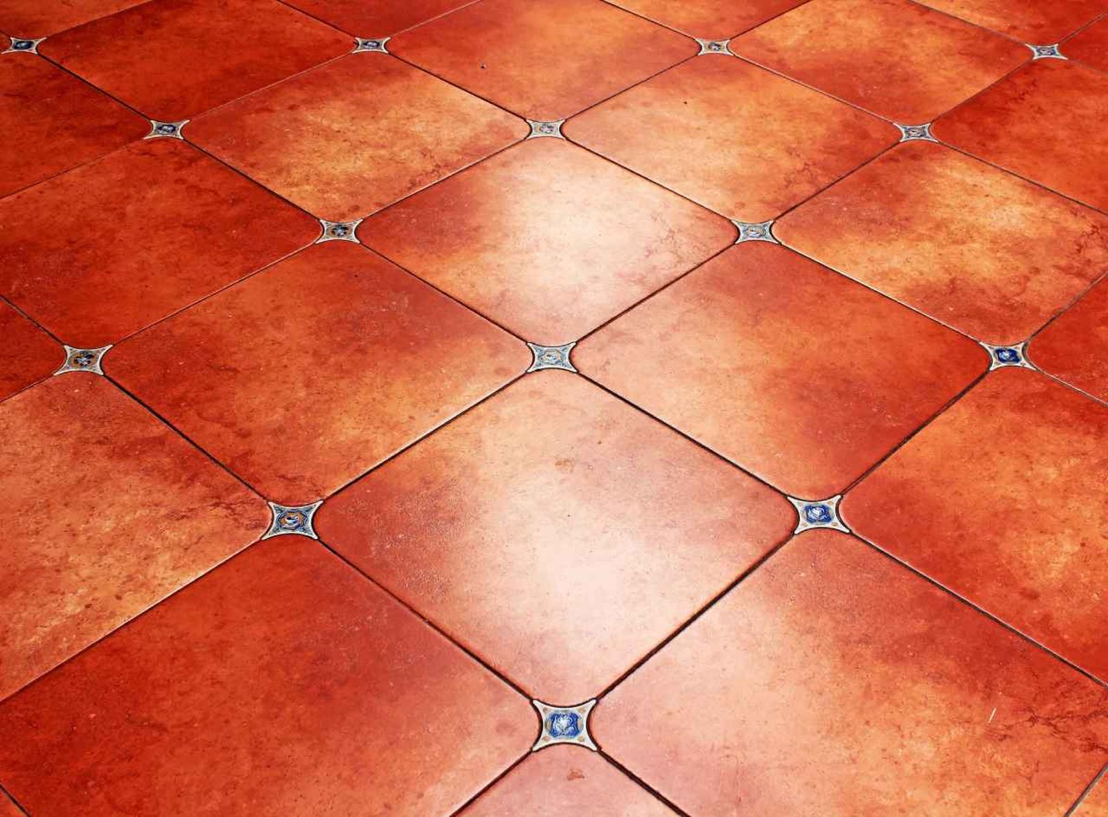 Suelo de cerámica restaurado con cera roja, mostrando un color rojo intenso y brillante.