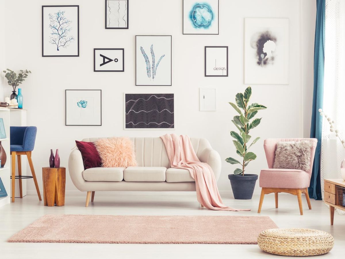 Salón acogedor con sofá beige y mucha decoración en las paredes.