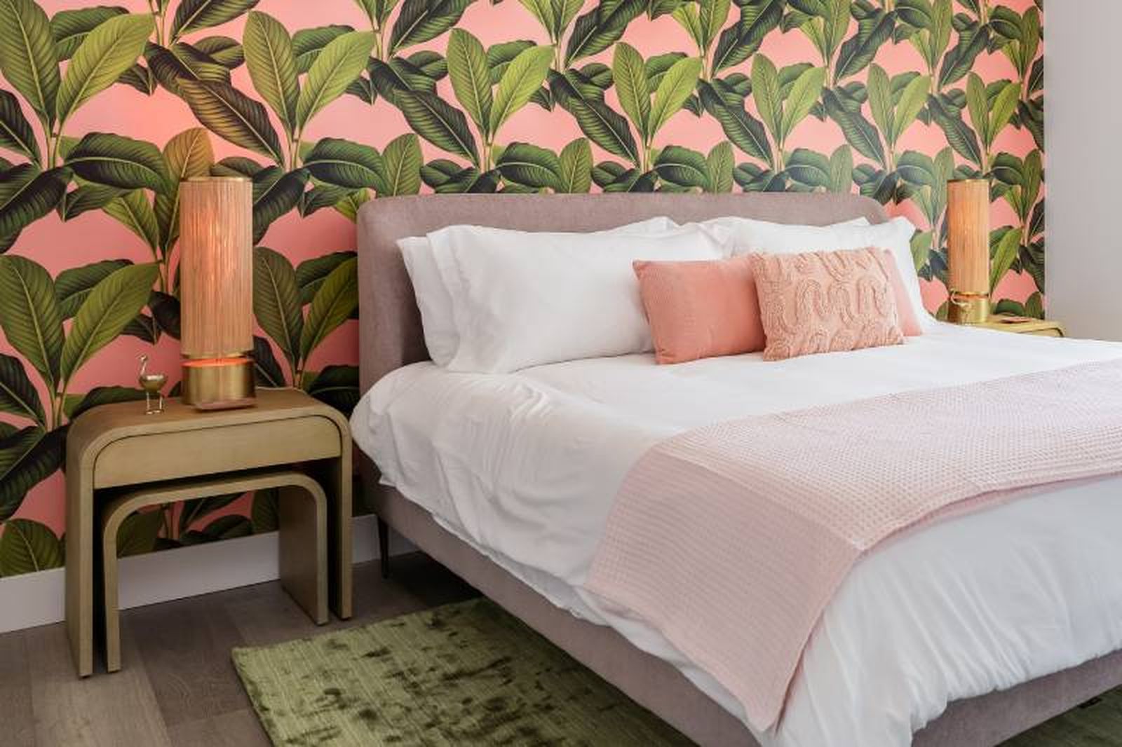 Dormitorio con papel pintado tropical en verde hoja y rosa.