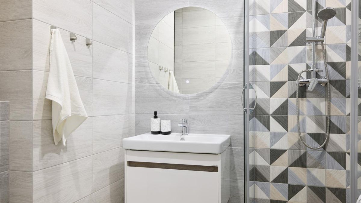 Baño pequeño con azulejos grandes en las paredes y azulejos pequeños en la zona de la ducha.