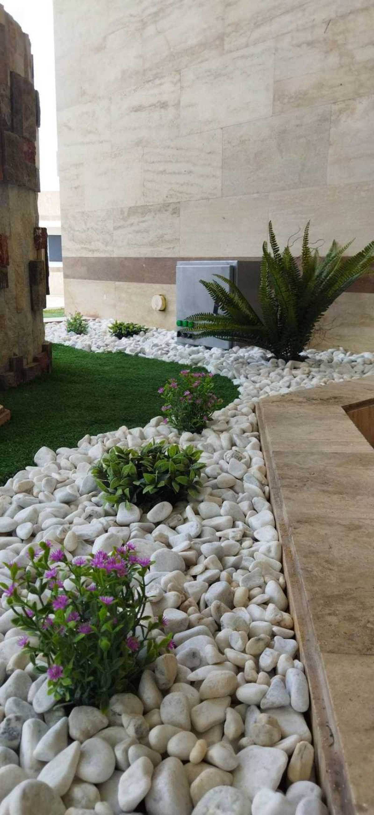 Jardín pequeño con césped artificial y piedras de estilo minimalista.