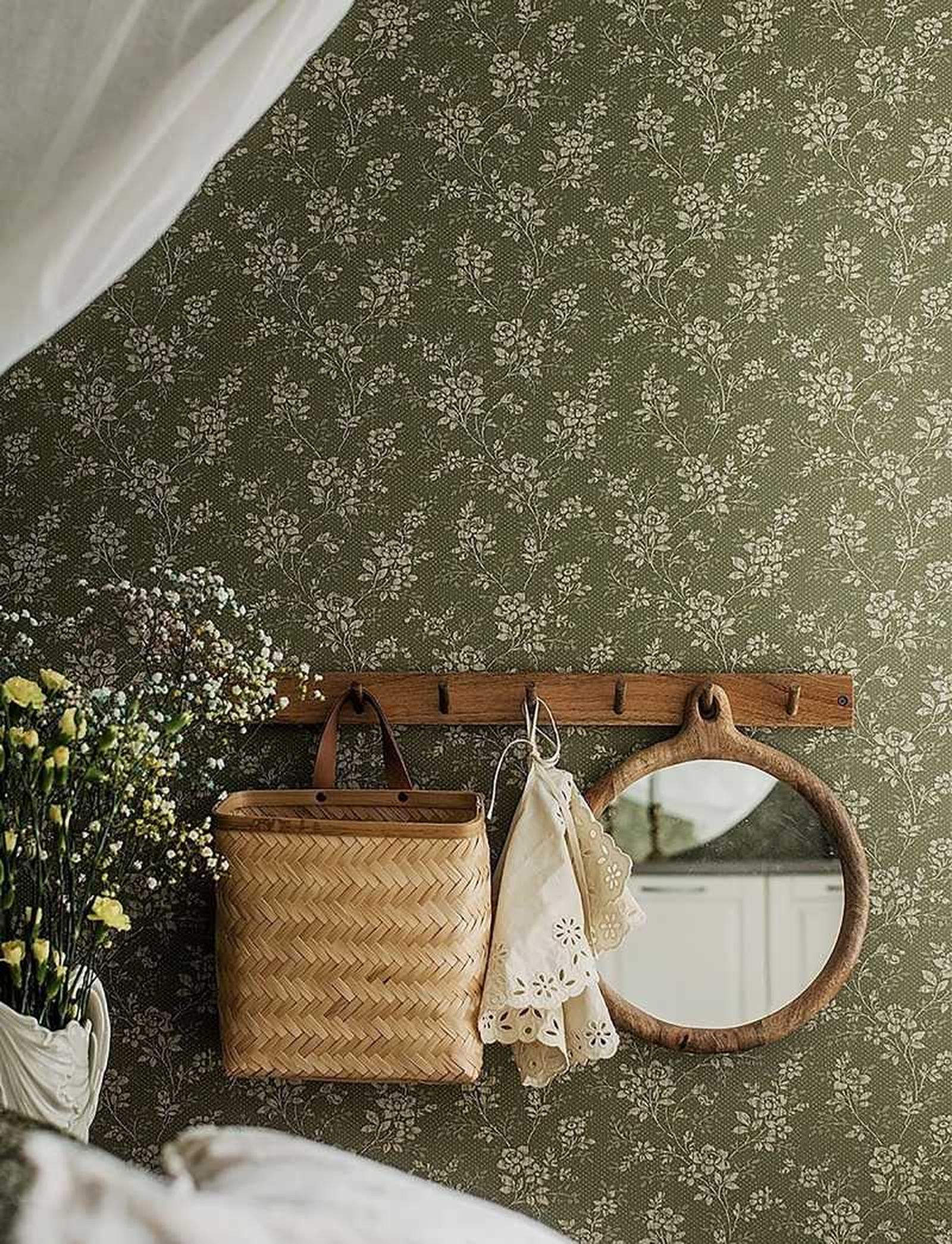 Pared decorada con papel pintado floral y complementos de madera y mimbre.