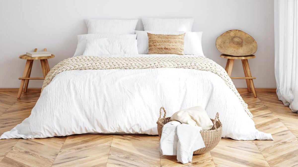 Dormitorio bohemio con cesta de mimbre en los pies de la cama.