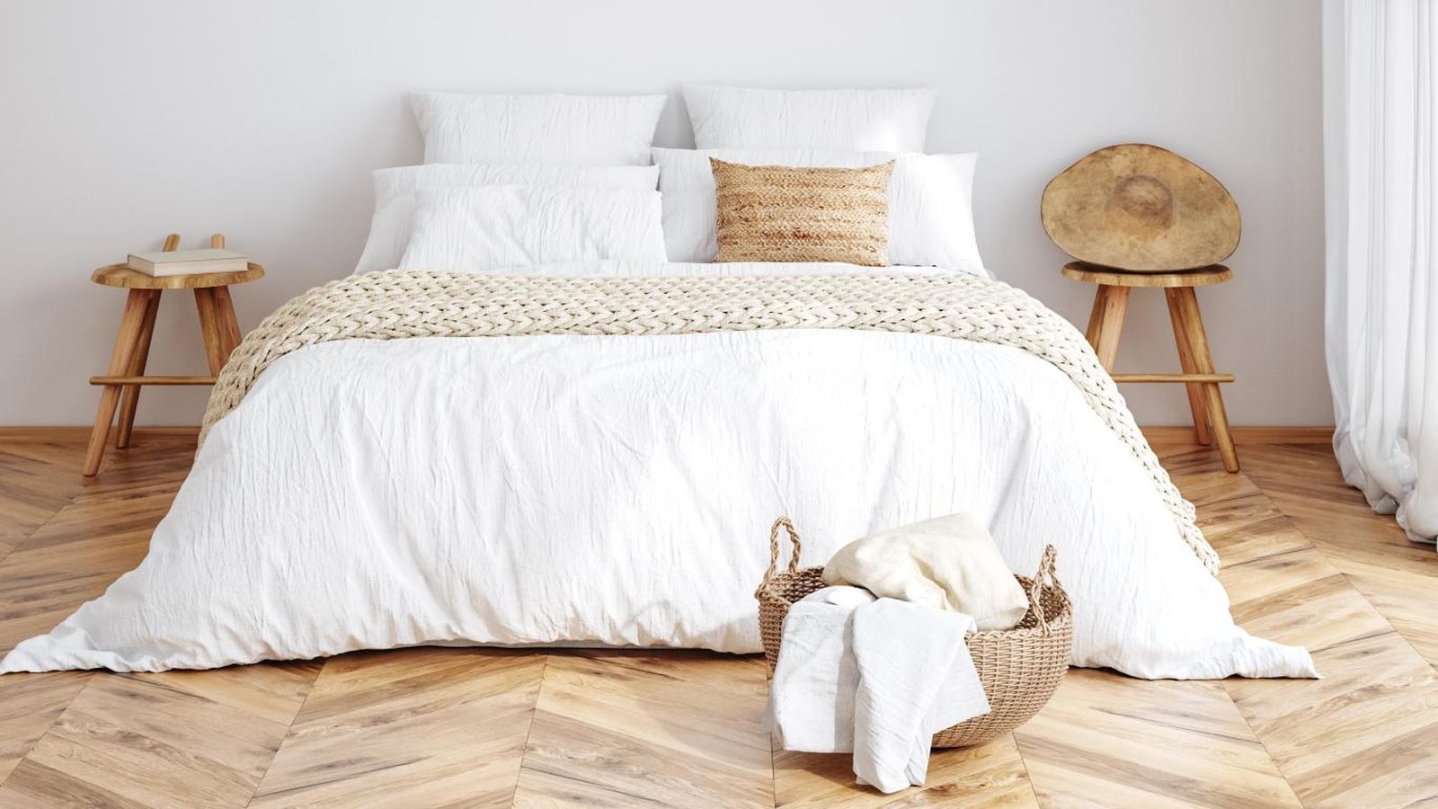 Dormitorio bohemio con cesta de mimbre en los pies de la cama.