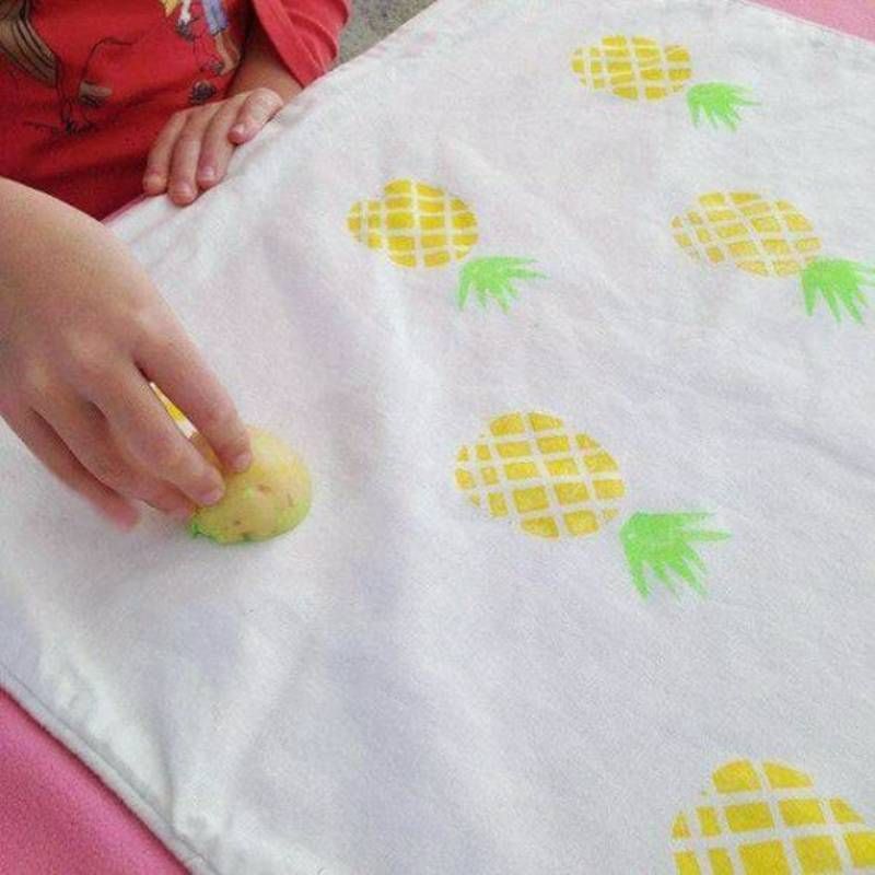Niño pintando piñas en una tela.