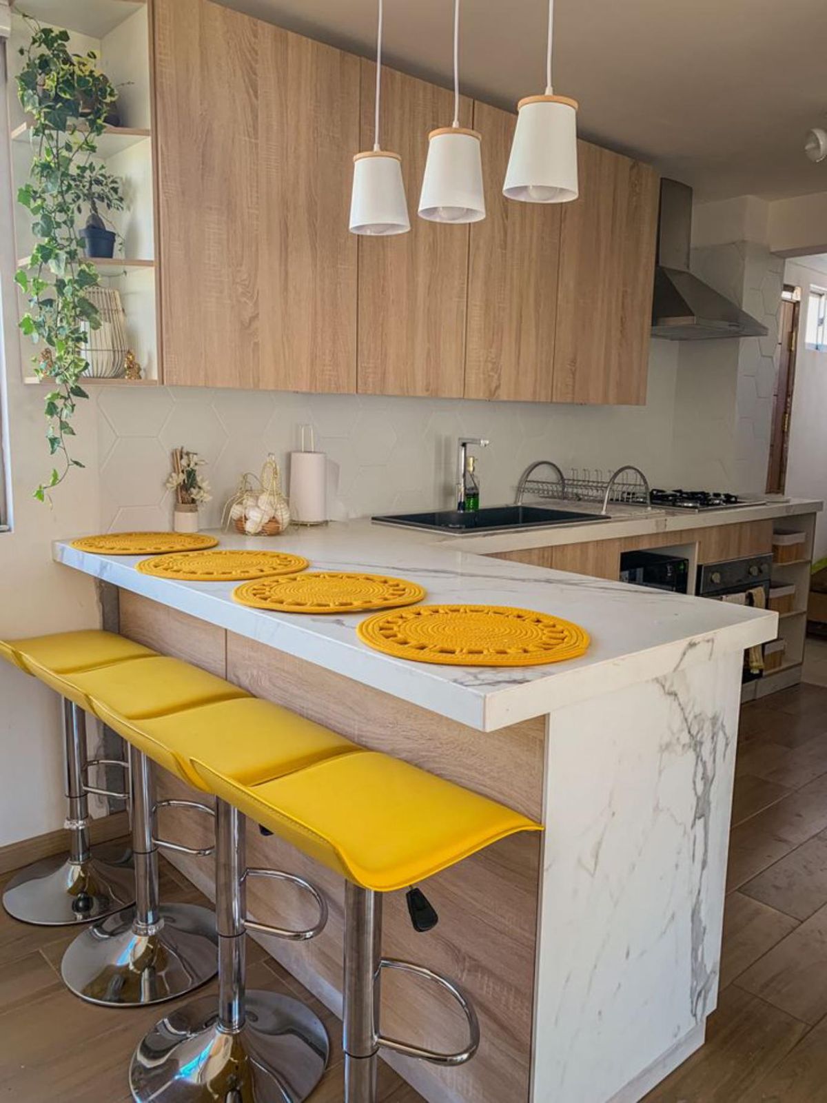Cocina con península decorada con complementos amarillos.