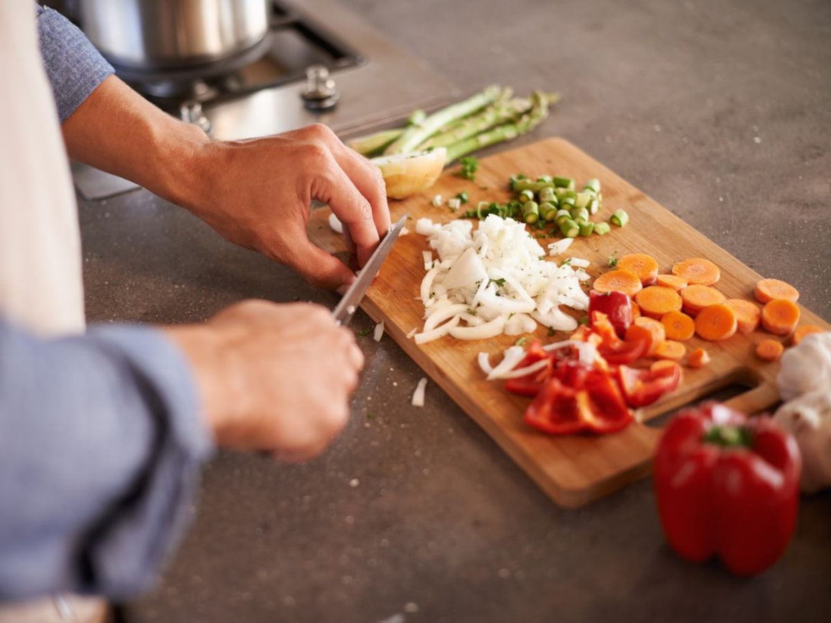 Cortar verduras en tabla de madera.