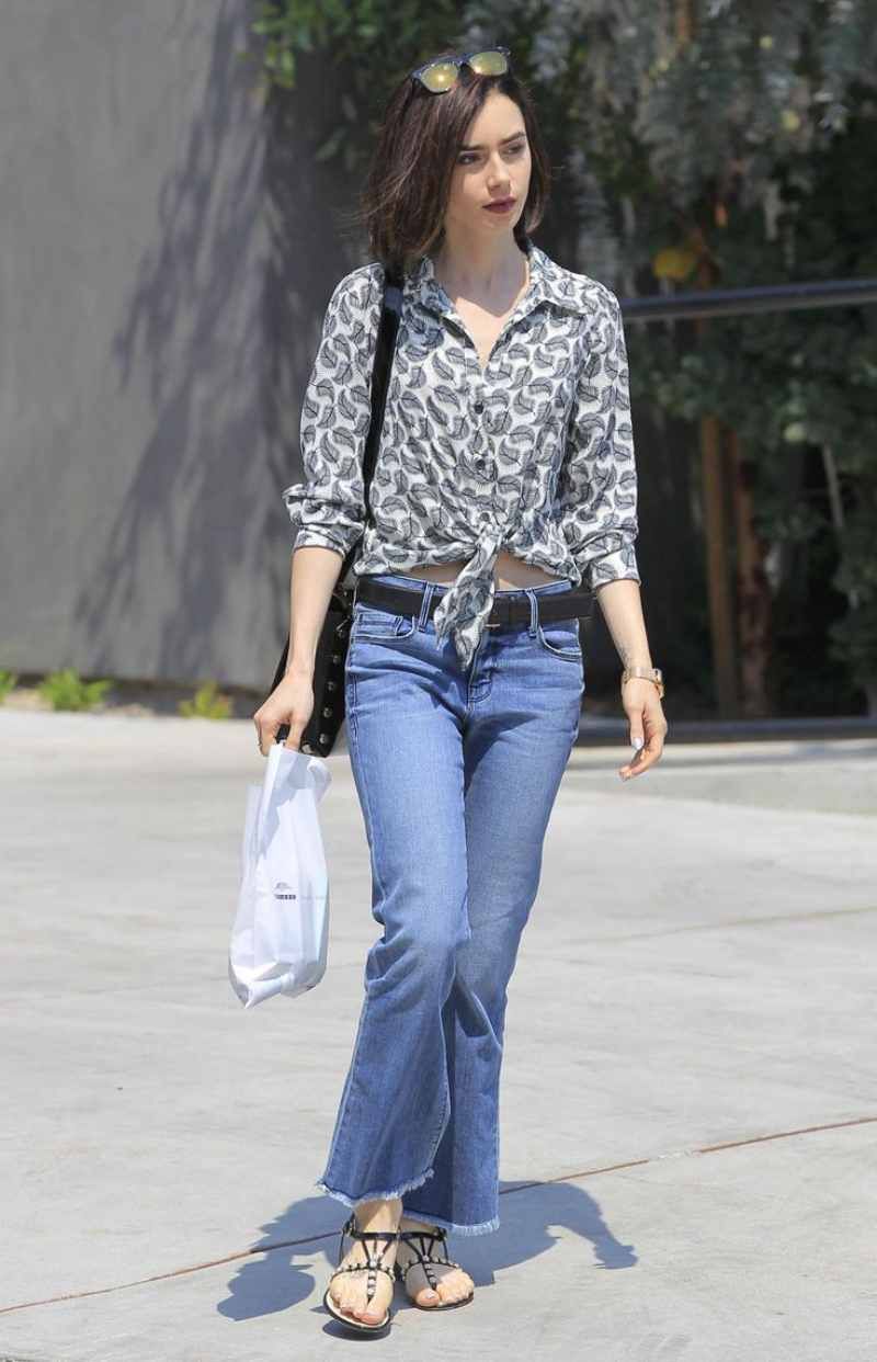 Lily Collins con camisa anudada y sandalias planas