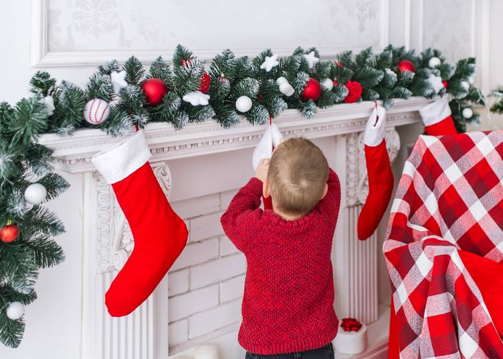 Niño buscando los regalos en un calcetín de Navidad.