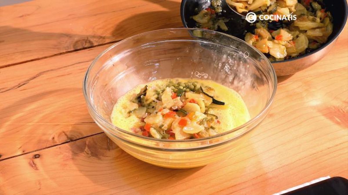 Incorpora las verduras pochadas, los guisantes y el jamón en el huevo batido