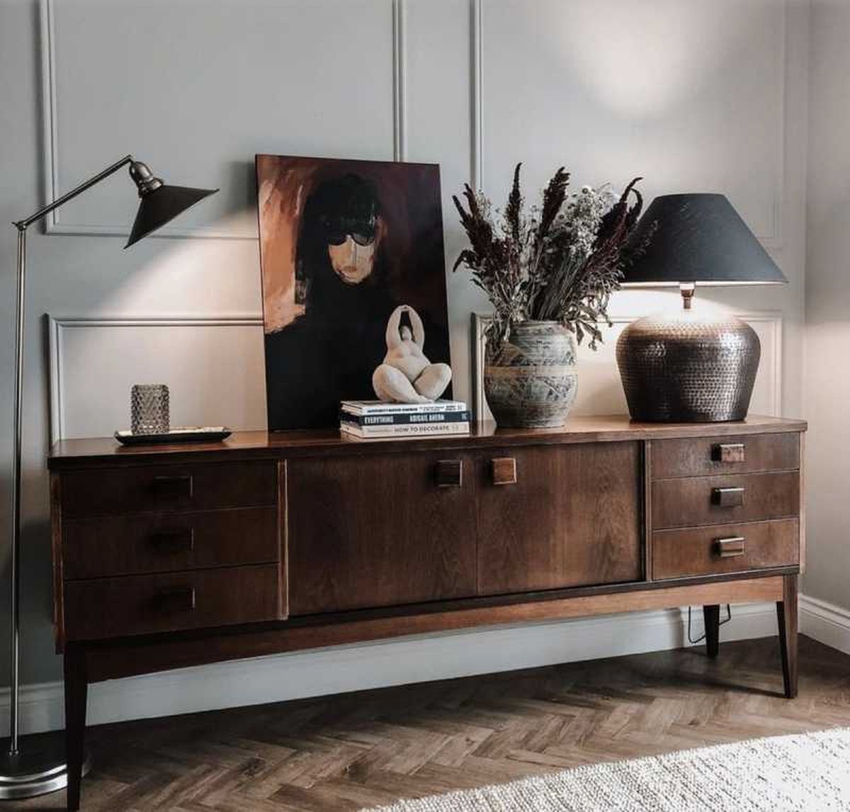 Mueble vintage oscuro decorado con arte y escultura.
