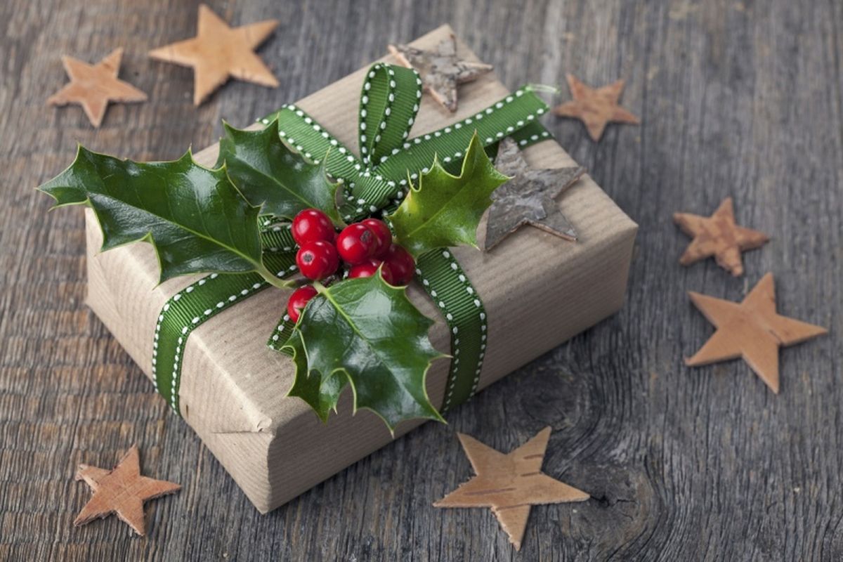 Regalo navideño envuelto con papel kraft, cuerda de yute y ramas de acebo.