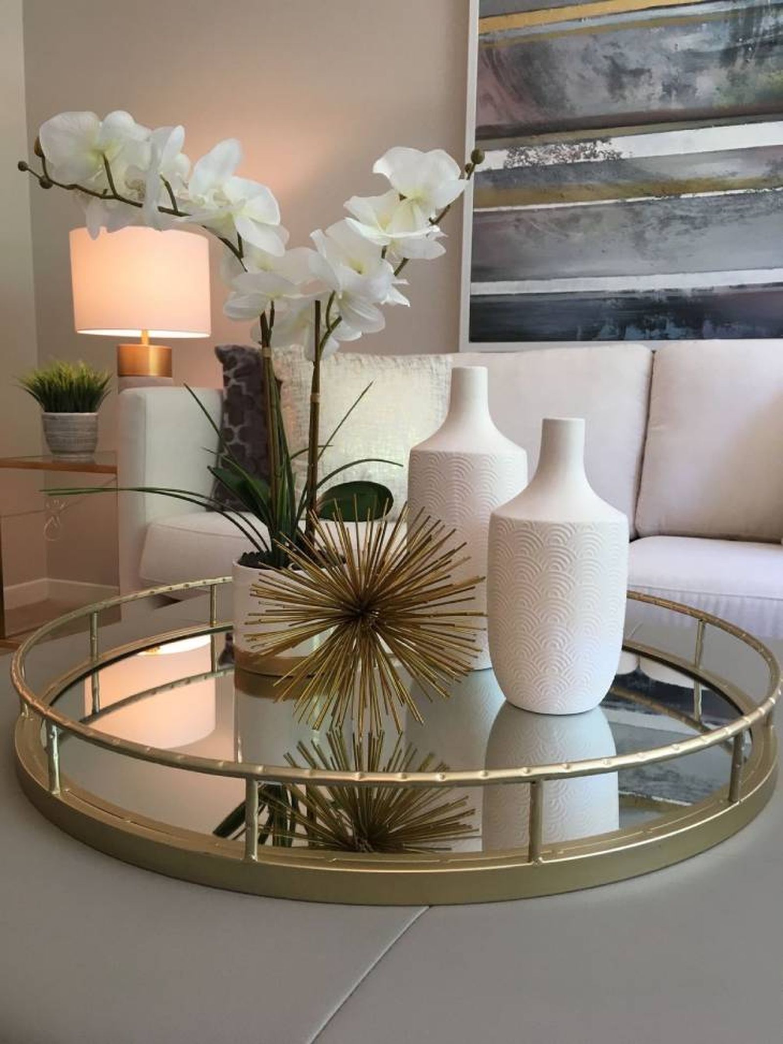 Mesa de centro decorada con una bandeja, flores y complementos.