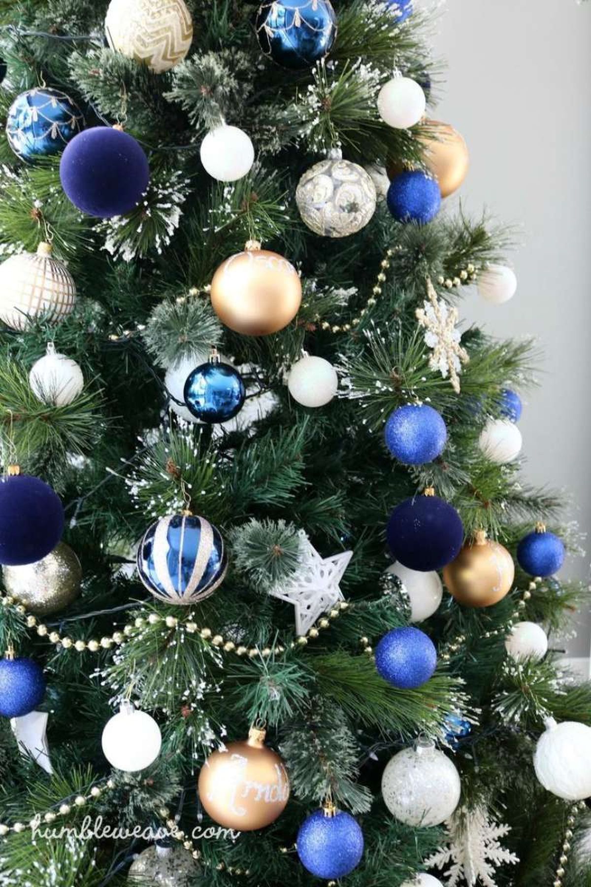 Árbol de Navidad con adornos en azul marino, blanco y dorado.