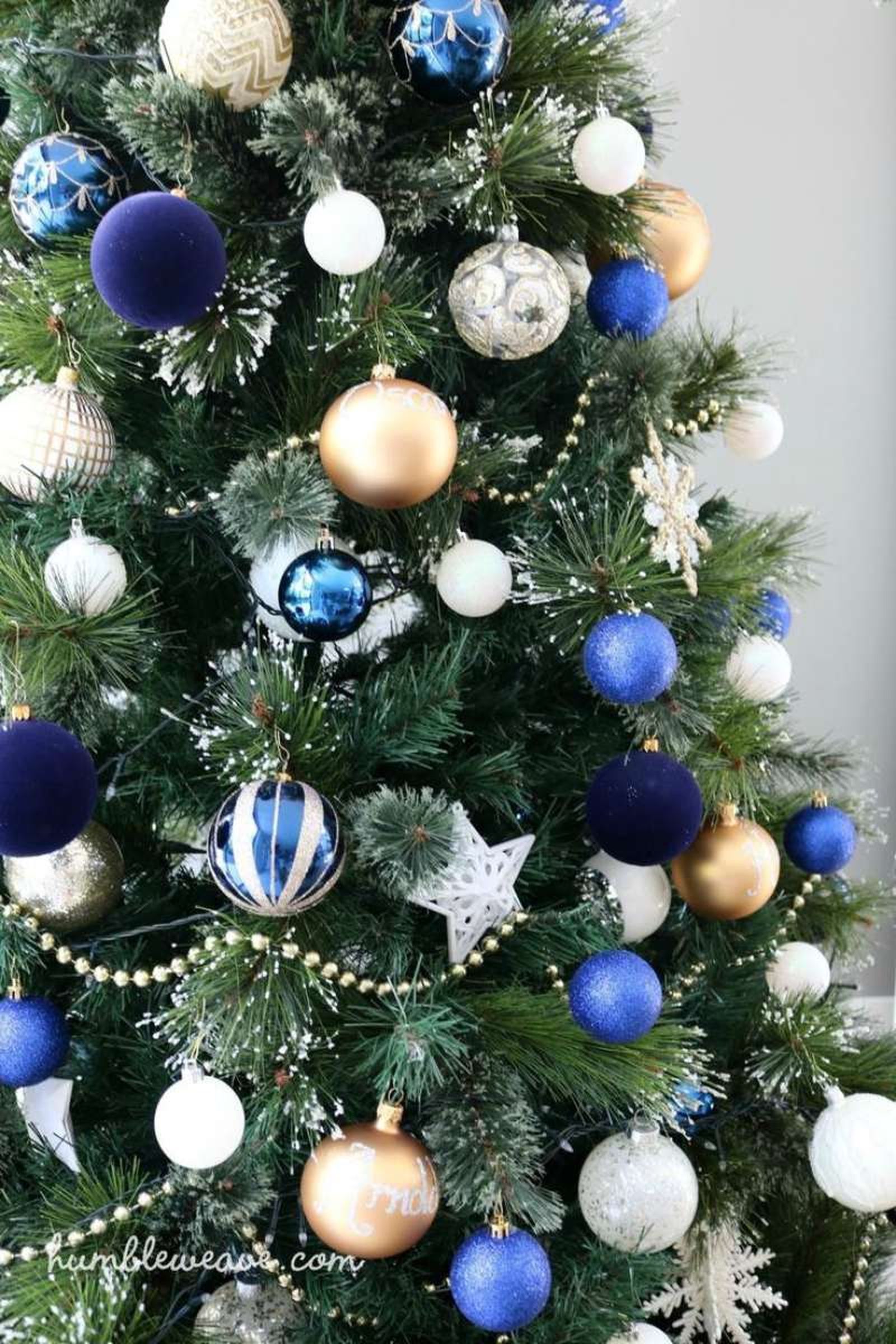 Árbol de Navidad con adornos en azul marino, blanco y dorado.