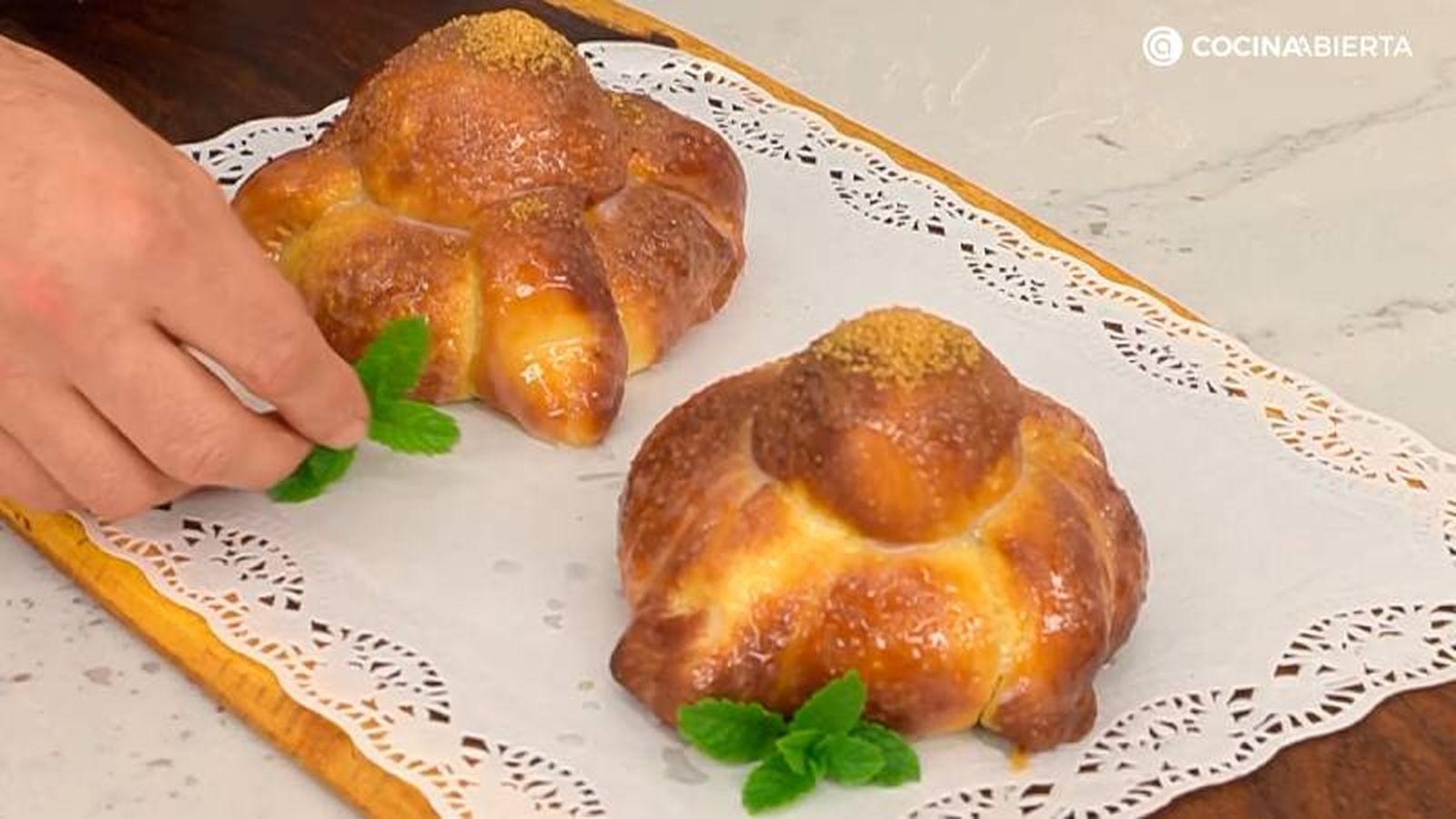 Unta el pan de muerto con una mezcla de leche y azúcar, y decora con azúcar moreno