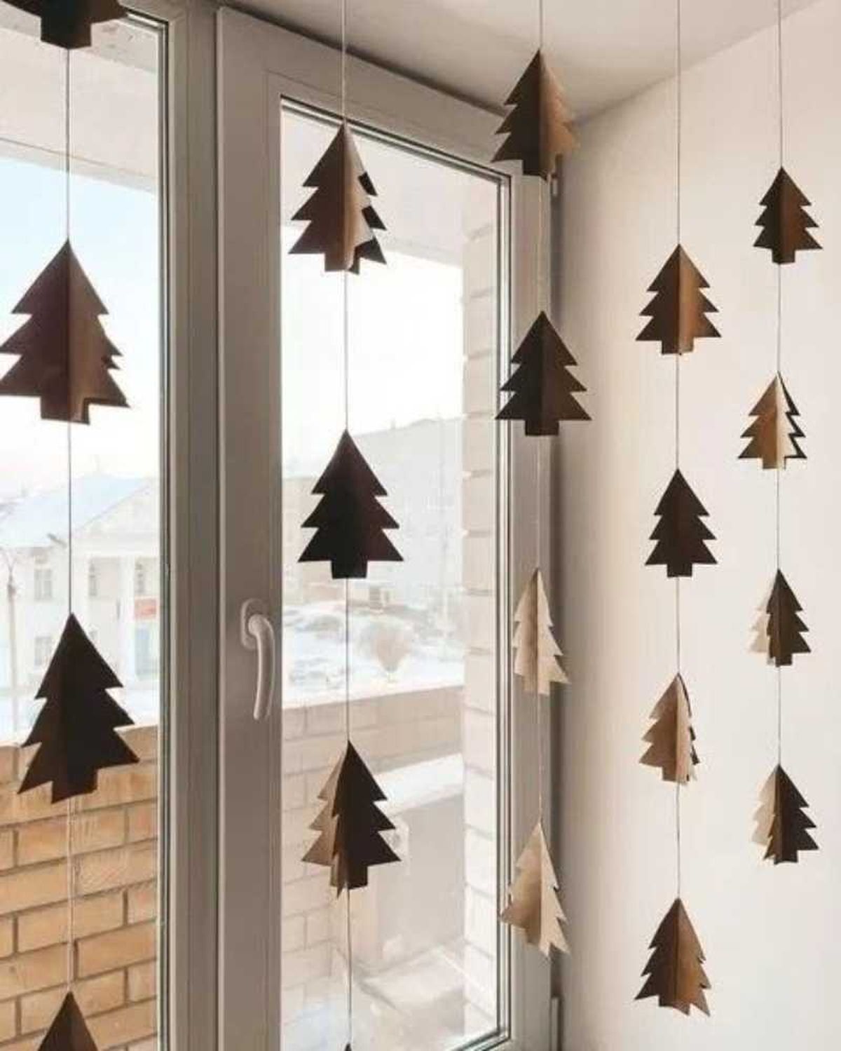 Ventana decorada con árboles de Navidad de papel.