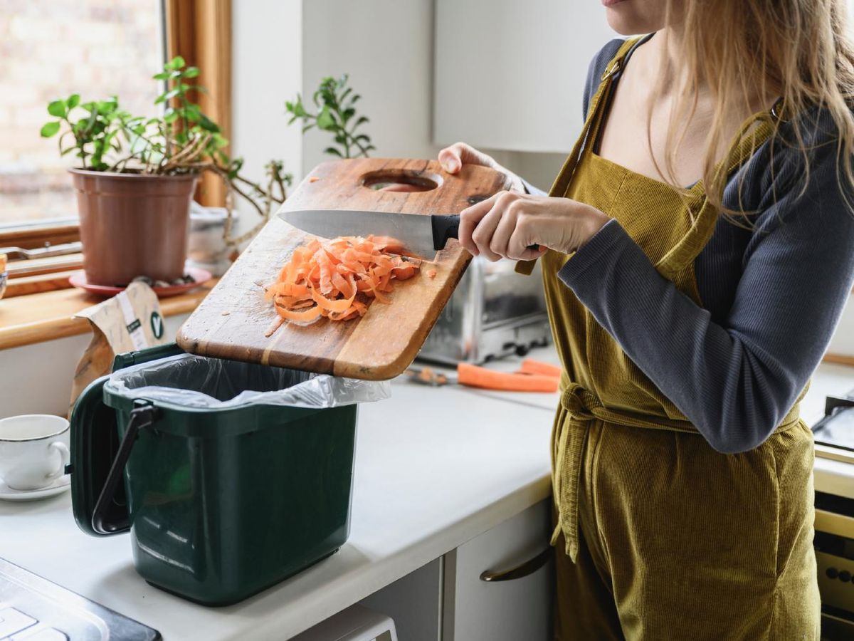 Mujer reciclando en la cesta de los residuos compostables.