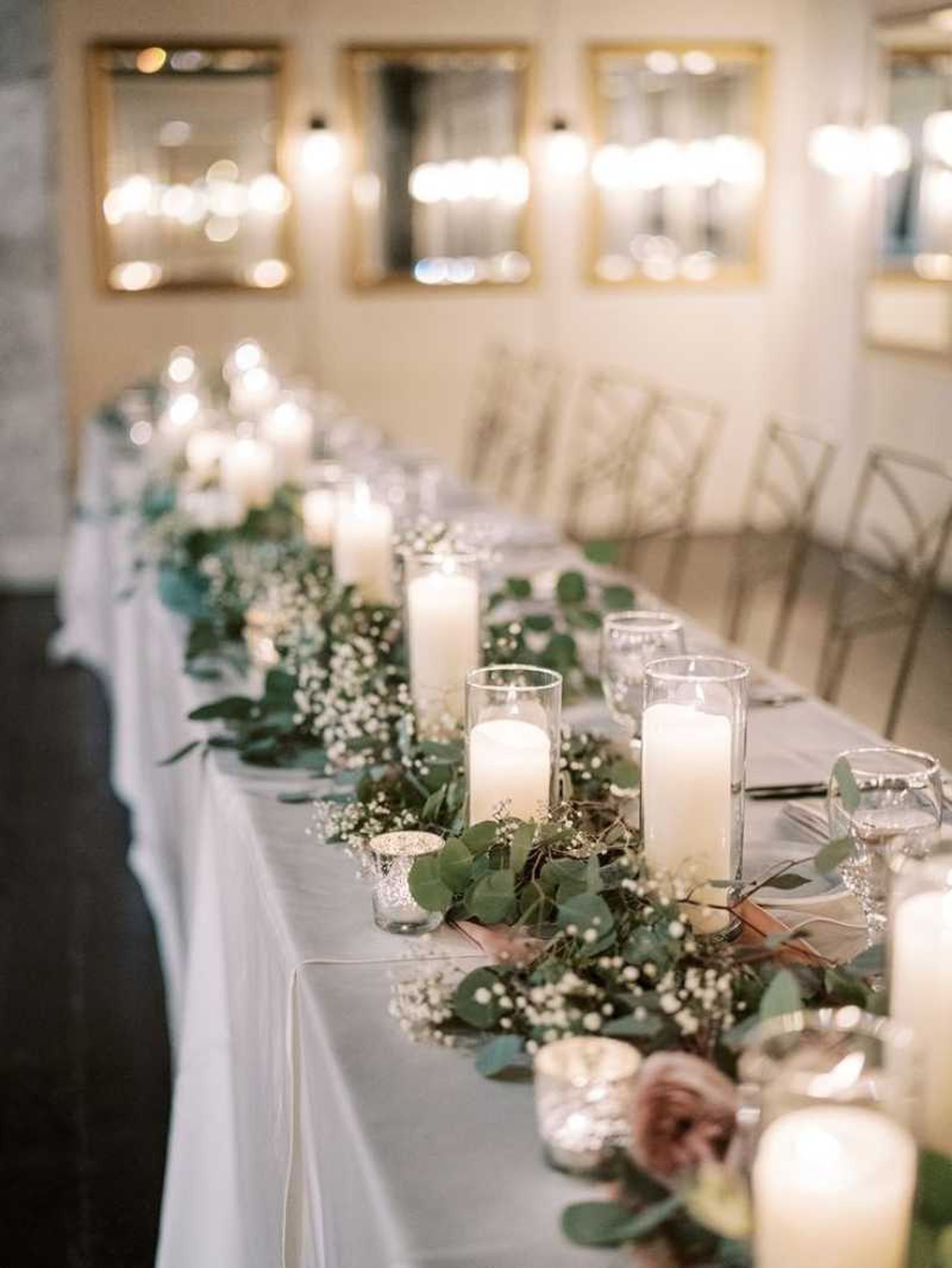 Centro de mesa para boda con hojas verdes y velas.