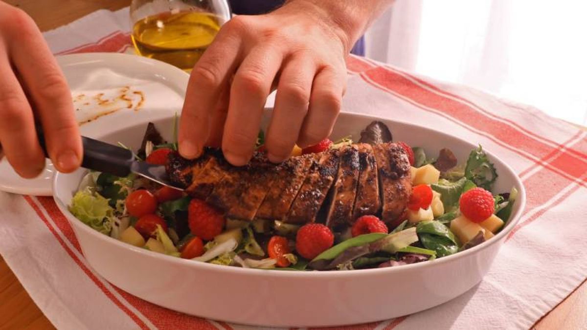 Monta tu ensalada de pollo comenzando con una base de lechuga, y añade el pollo, queso emmental, tomates cherry y frambuesas para un toque fresco y delicioso