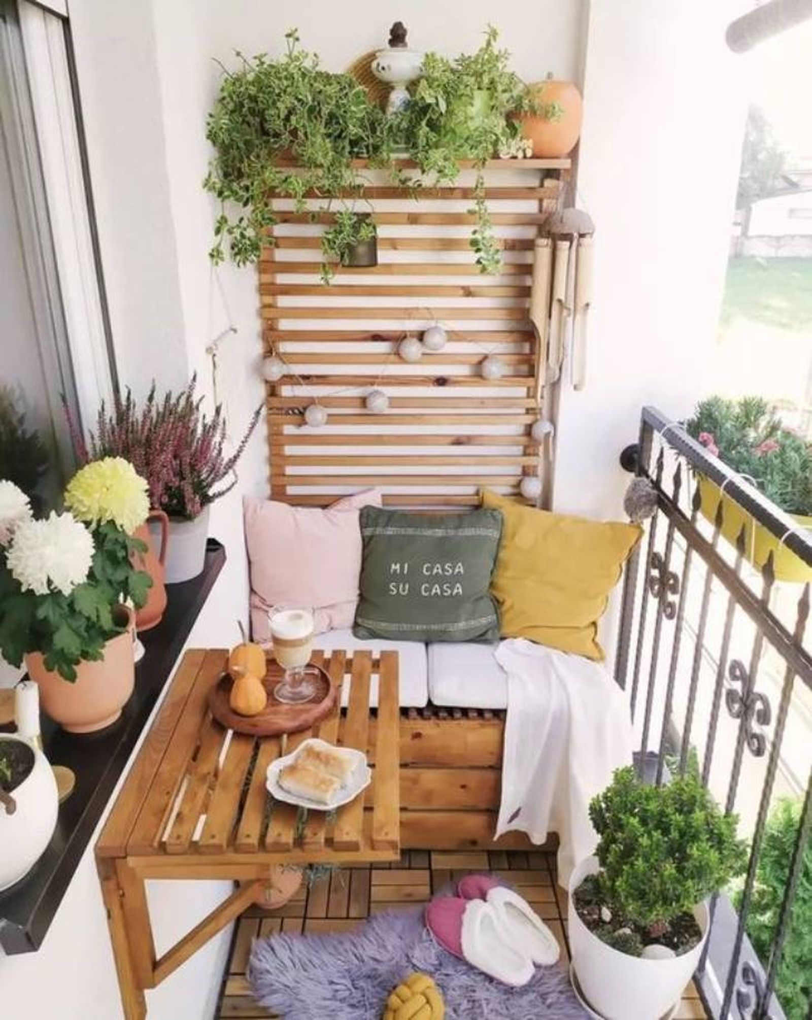 Balcón pequeño con banco y mesa abatible de madera.