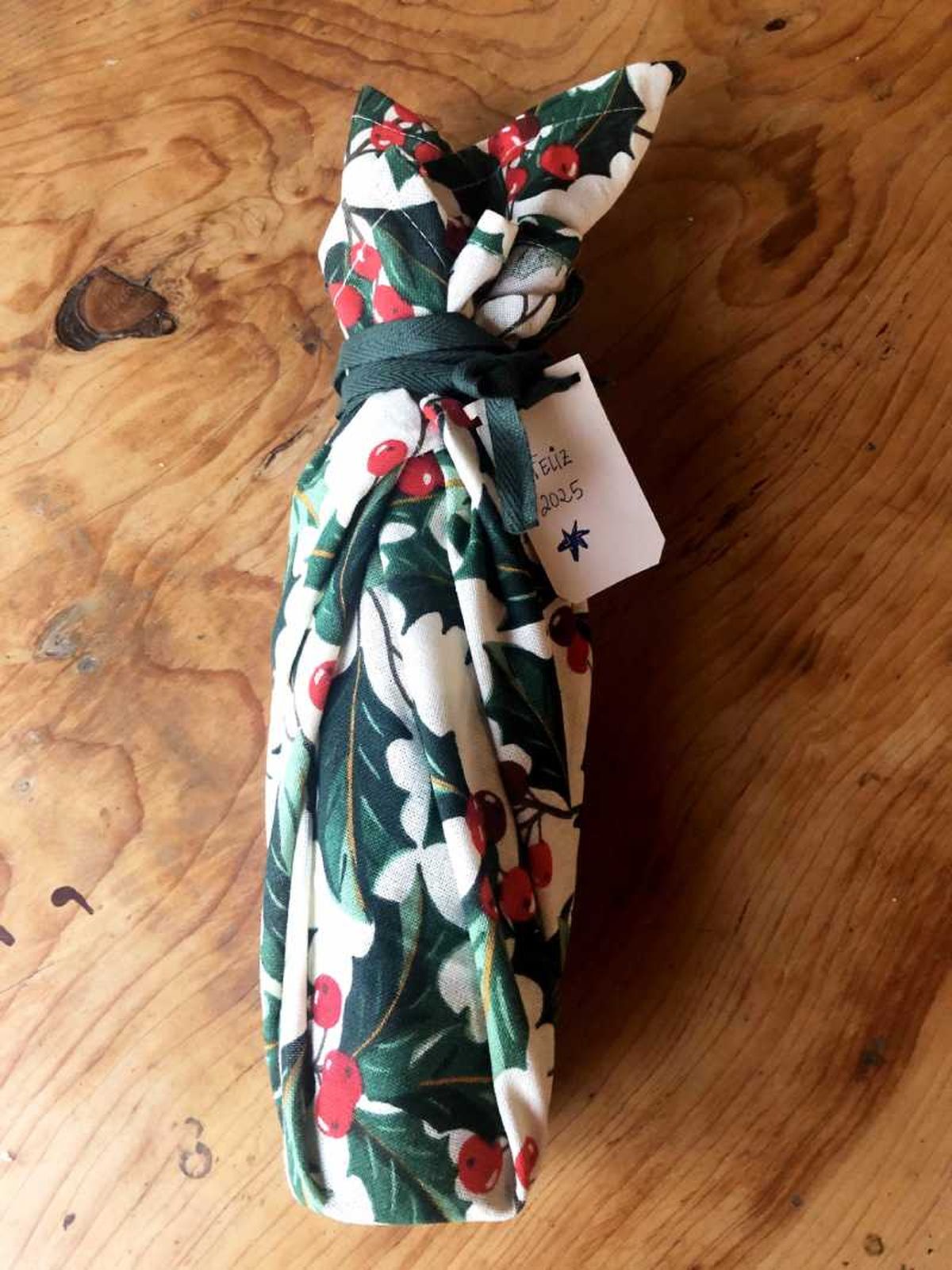 Decora con un lazo la botella envuelta con tela furoshiki.nvolver una botella.