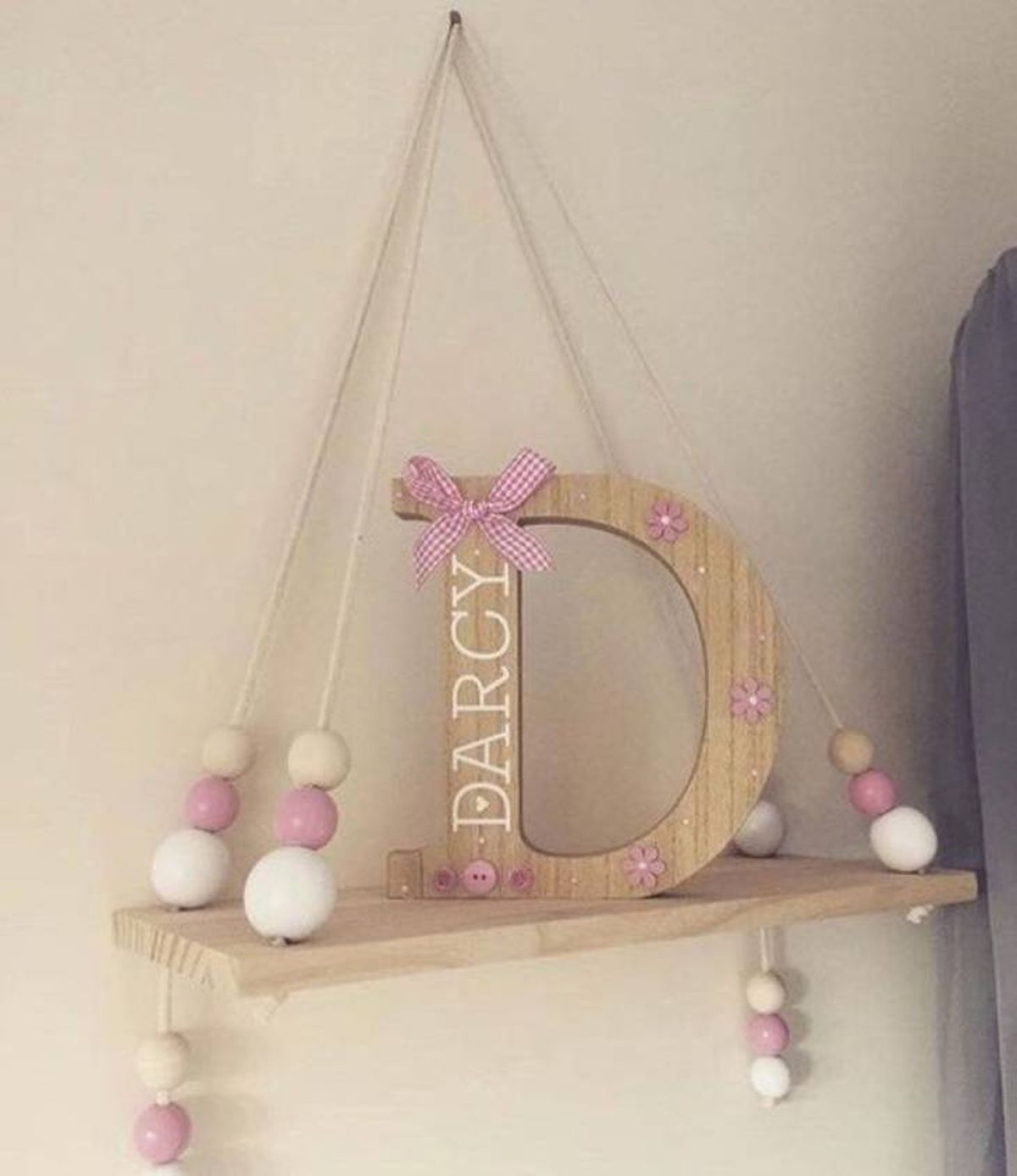 Letra D decorada con adornos de madera y lazos.