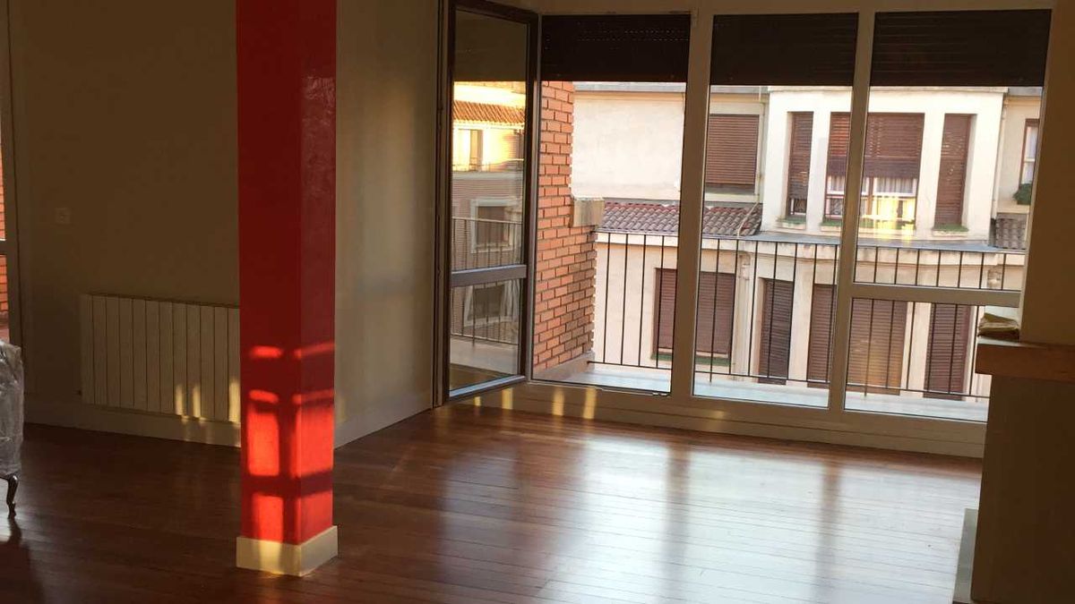 Salón reformado con columna roja de un piso en Bilbao.