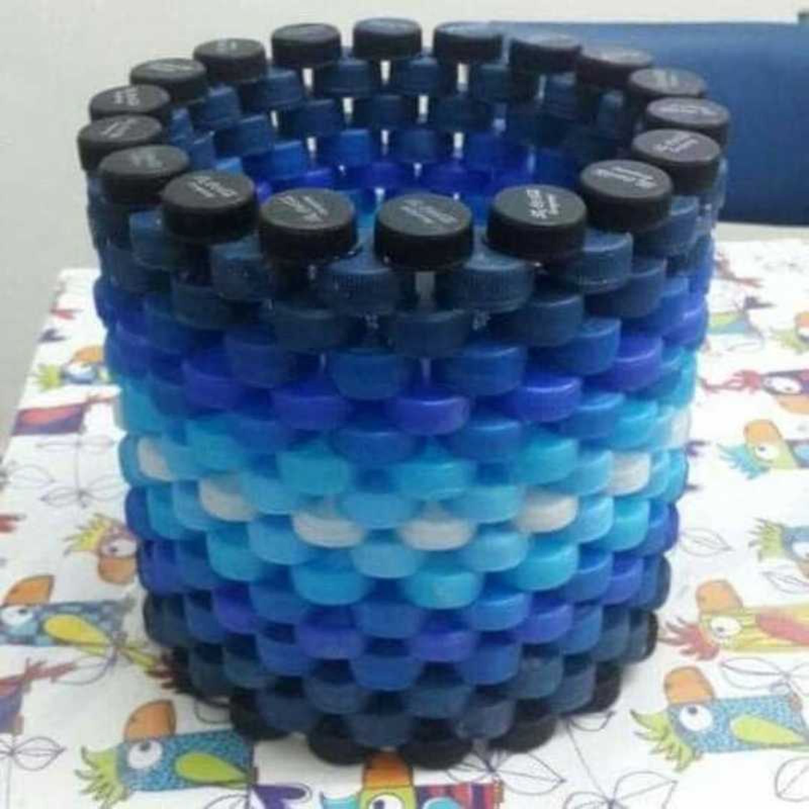 Cubo decorativo hecho con tapones de plástico.