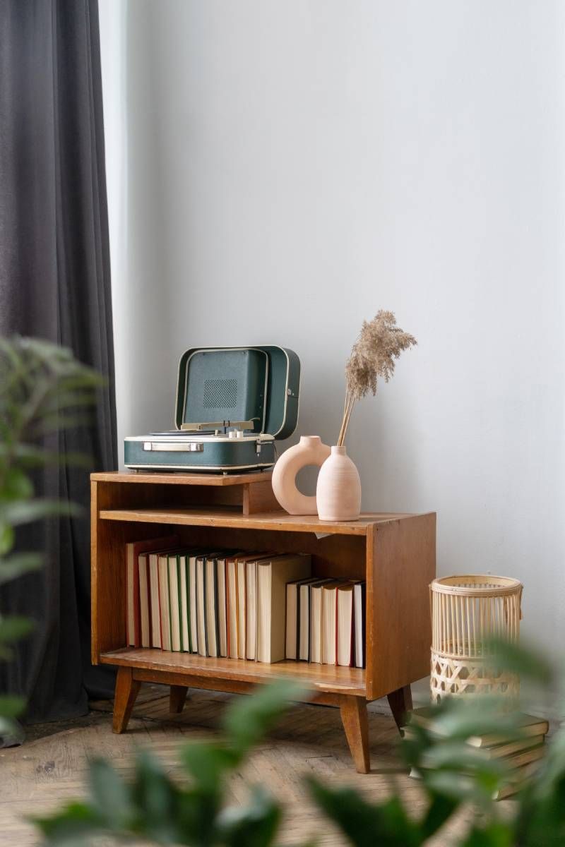 Mueble antiguo decorado con un tocadiscos y un jarrón con flores.