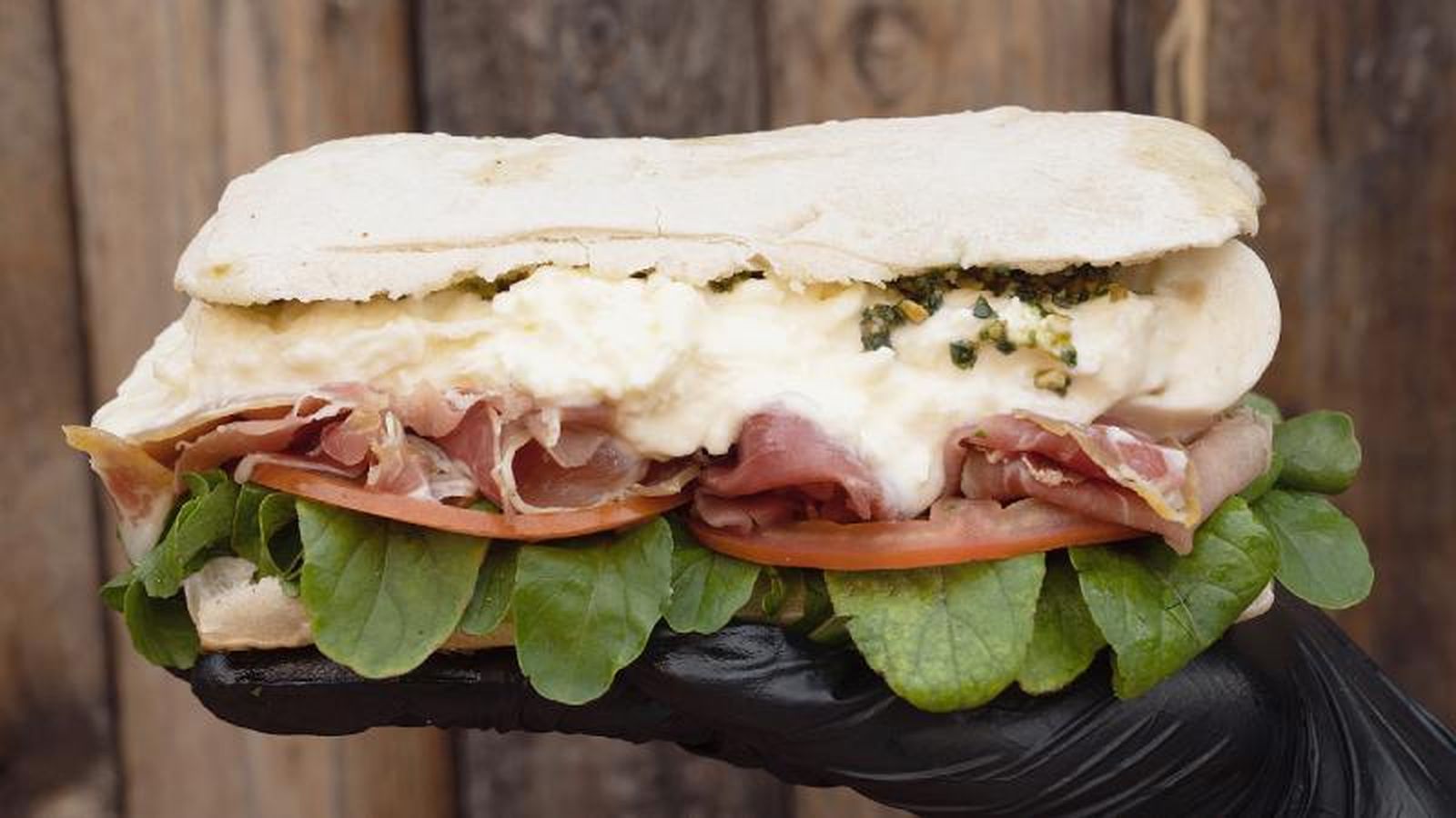 Bocadillo de burrata, prociutto, pesto, tomate y rúcula