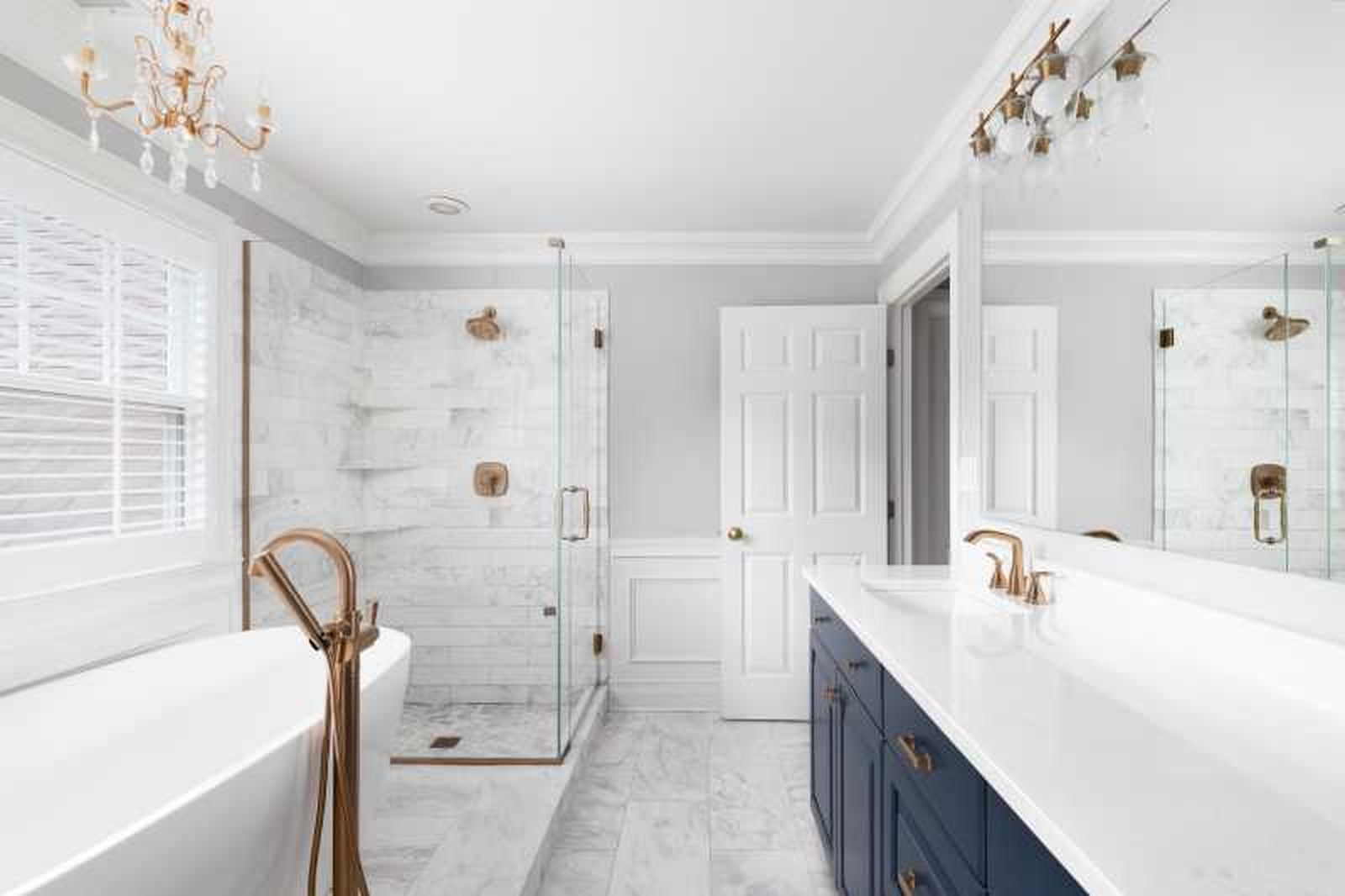 Baño blanco elegante con acabados metálicos dorados.