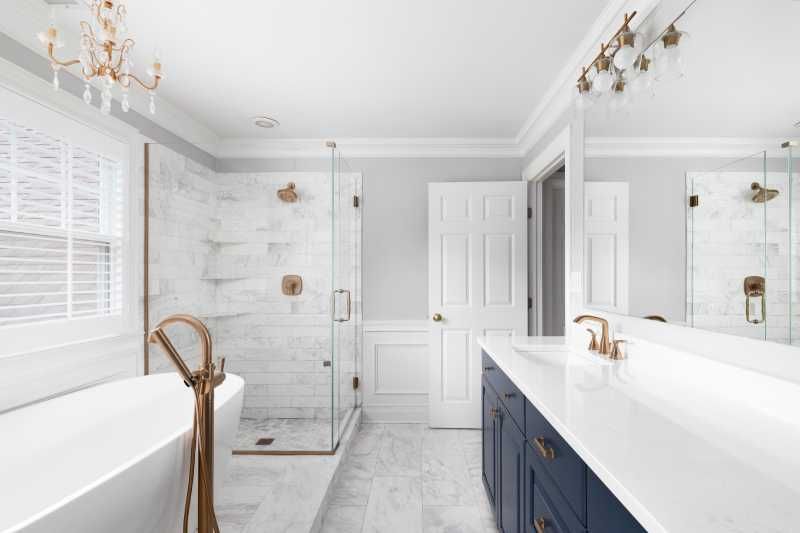 Baño blanco elegante con acabados metálicos dorados.