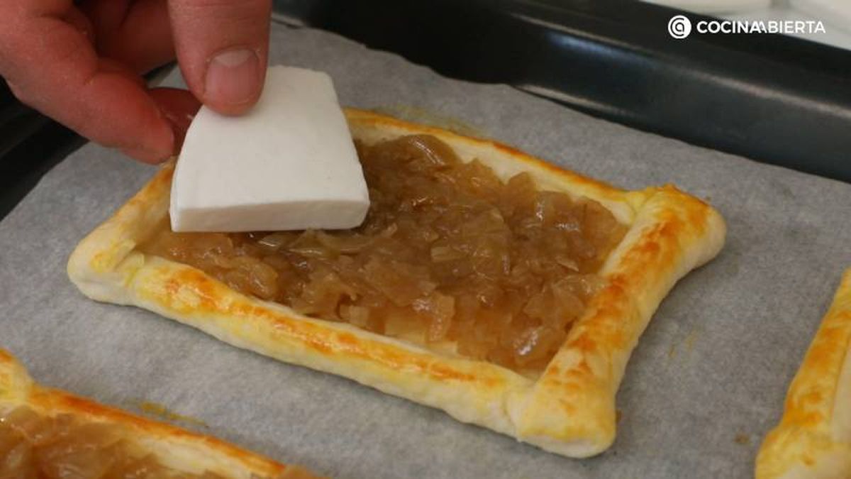 Cubre el hojaldre horneado con cebolla caramelizada y queso de cabra