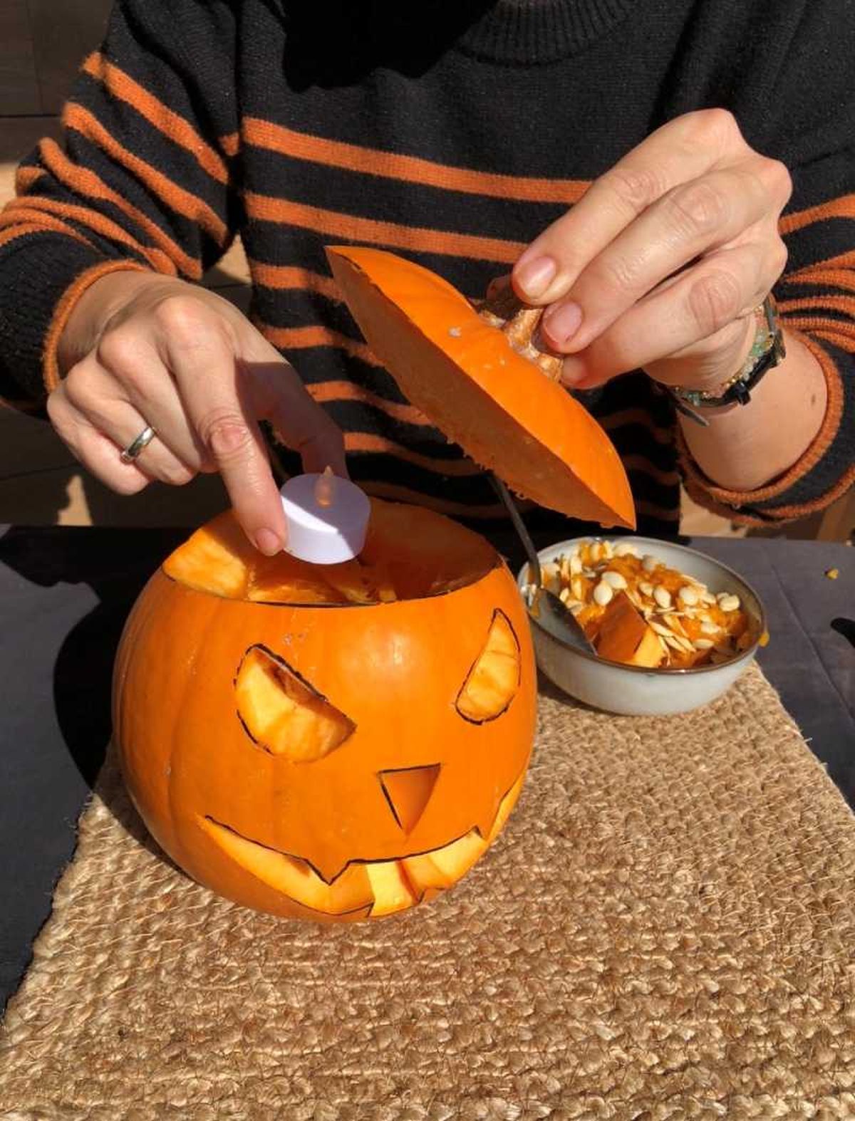 Meter vela de pilas dentro de la calabaza de Halloween.