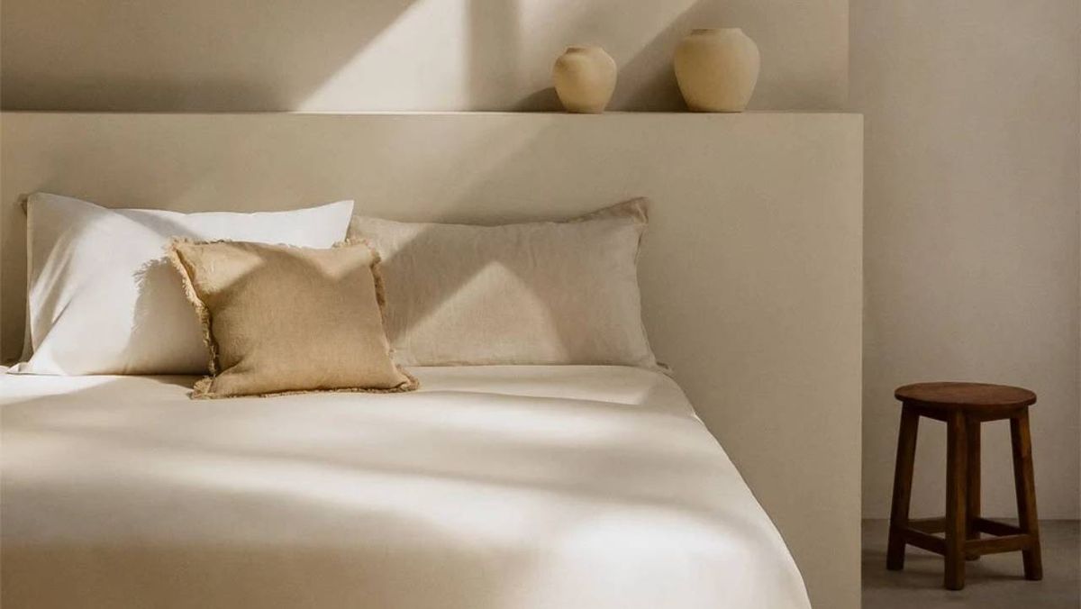 Dormitorio de estilo mediterráneo con silla de madera y vasijas.