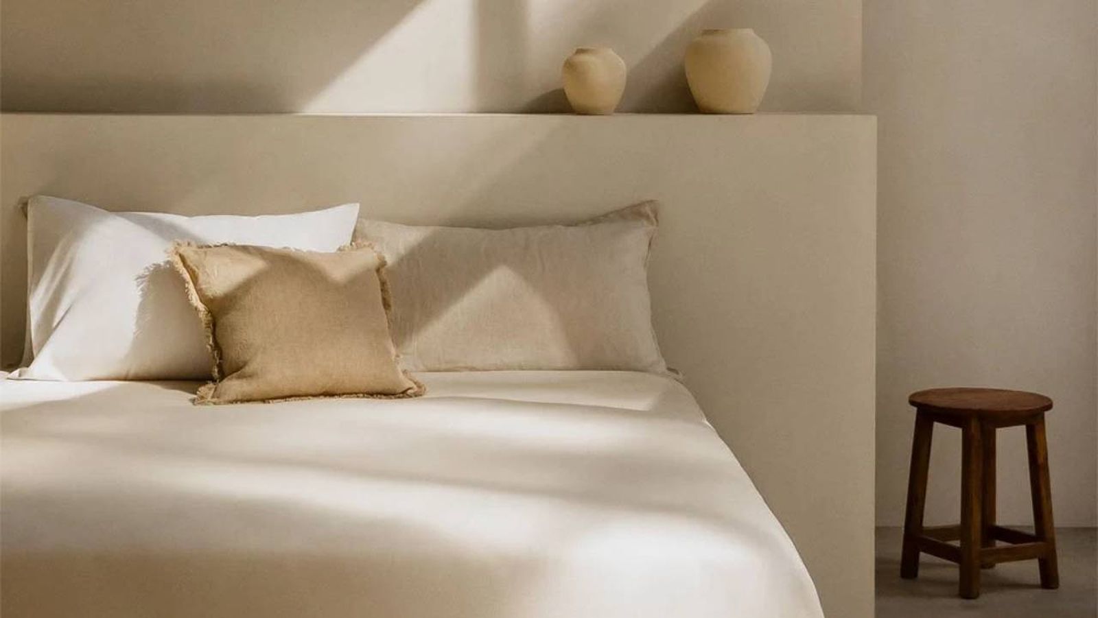 Dormitorio de estilo mediterráneo con silla de madera y vasijas.