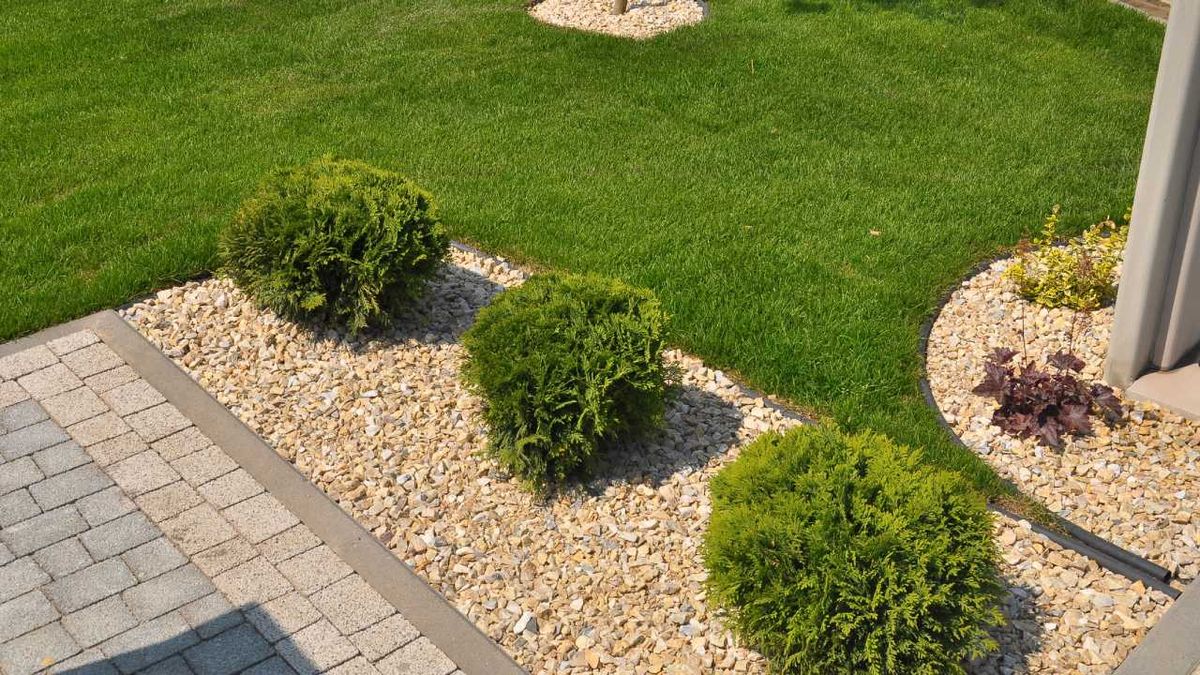 Jardín pequeño con césped artificial y piedras.