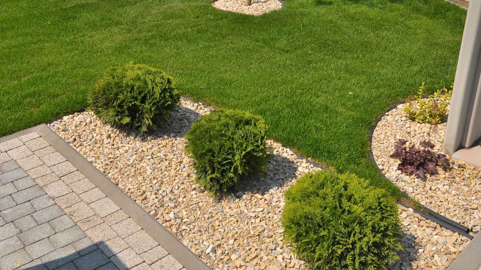 Jardín pequeño con césped artificial y piedras.