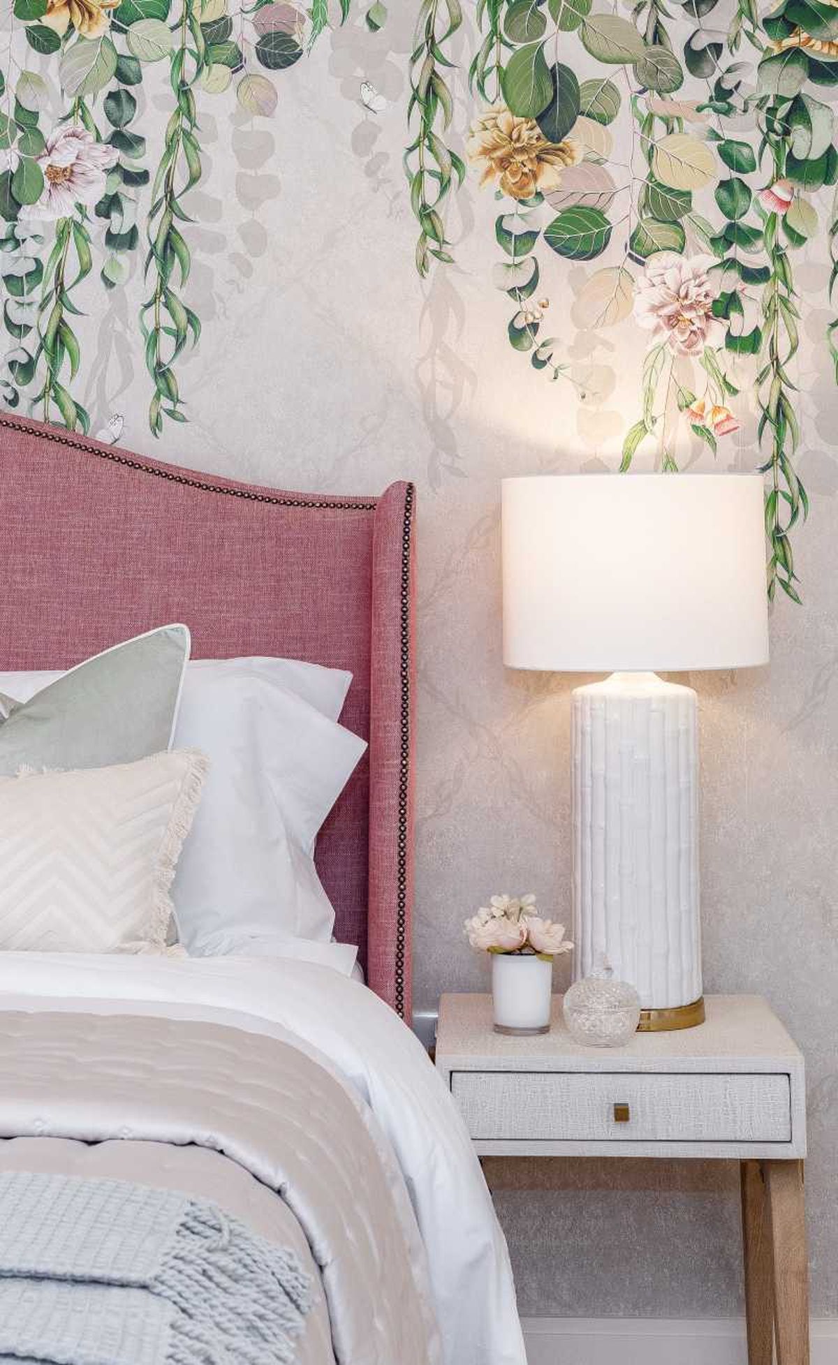 Dormitorio con papel pintado floral sencillo en el cabecero.