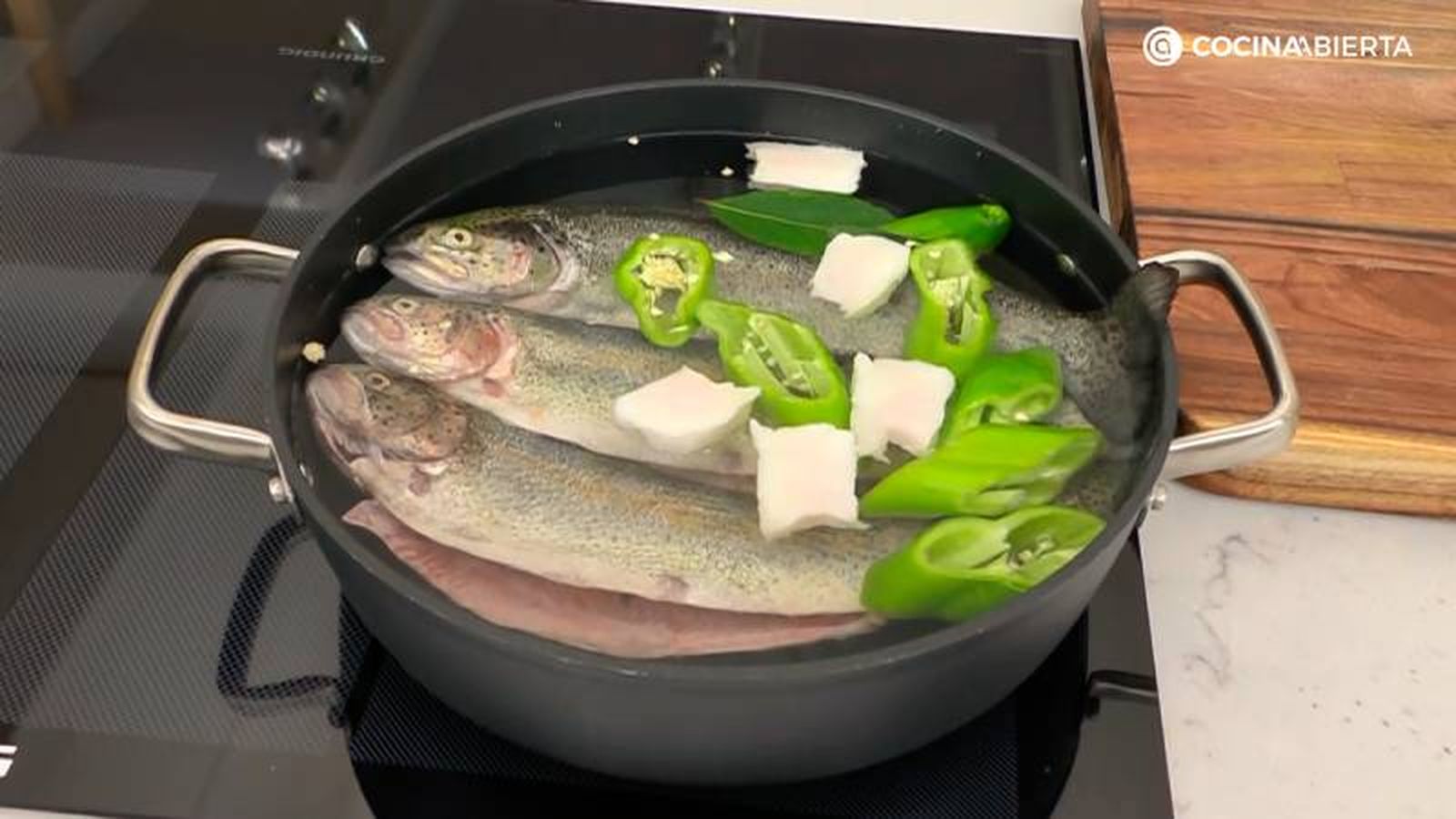 Calienta una cazuela con agua con las truchas, el pimiento verde y el tocino ibérico