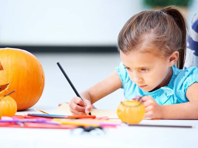 Niña coloreando dibujos otoñales.