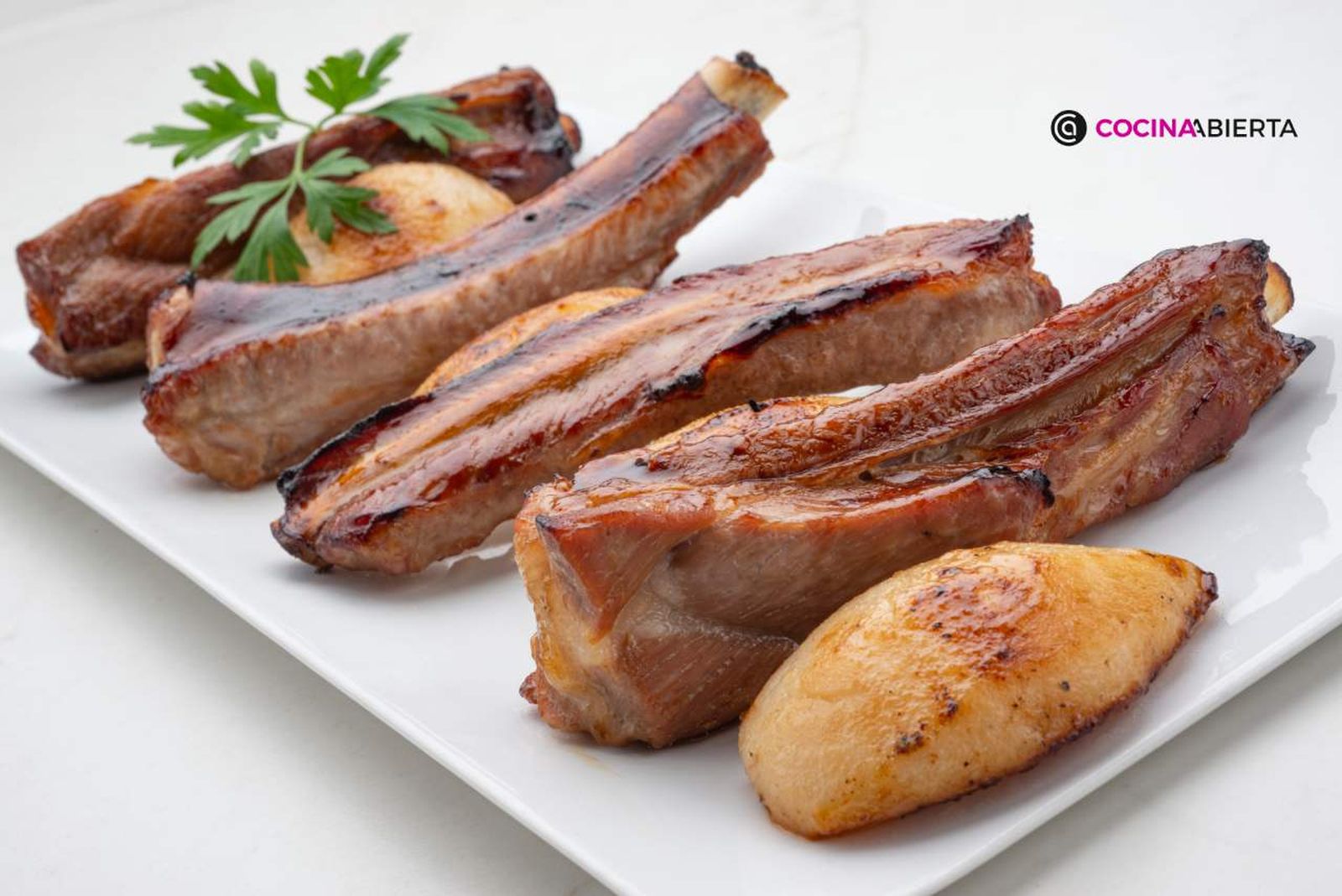 Jugosas costillas de cerdo asadas, acompañadas de peras, como guarnición
