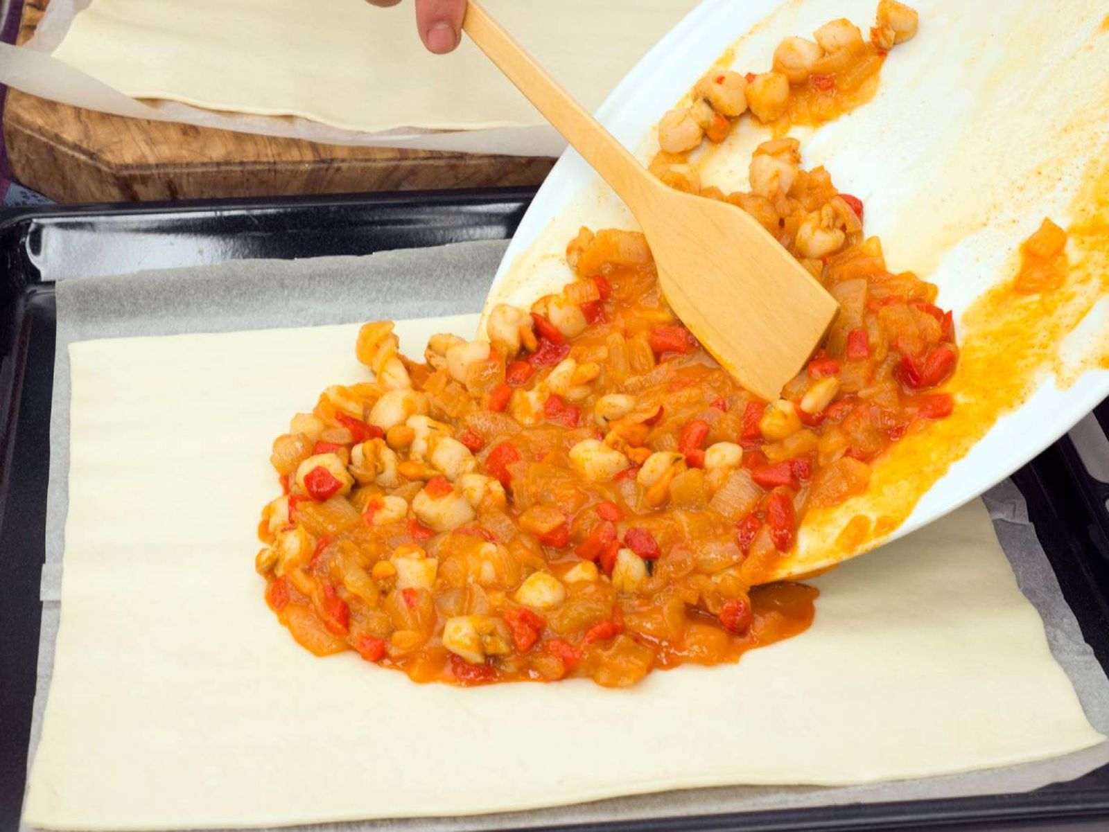 Extensión del relleno de zamburiñas y sofrito sobre la masa.