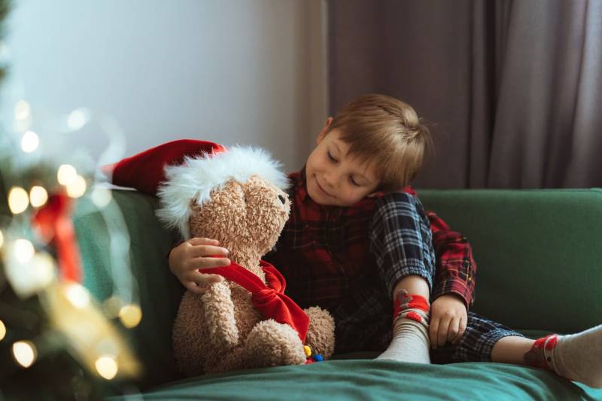 Niño en un sofá con un osito navideño.