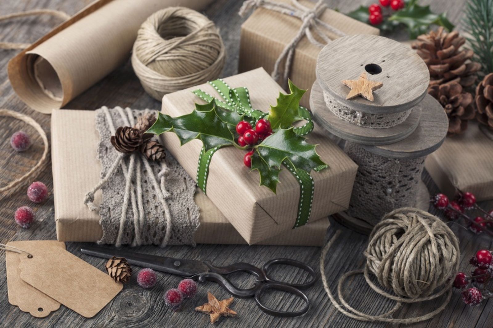 Regalos de Navidad envueltos con papel kraft y decorados con cuerda de yute y ramas de acebo.