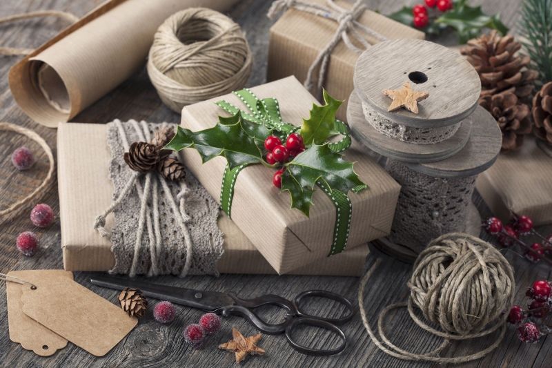 Regalos de Navidad envueltos con papel kraft y decorados con cuerda de yute y ramas de acebo.