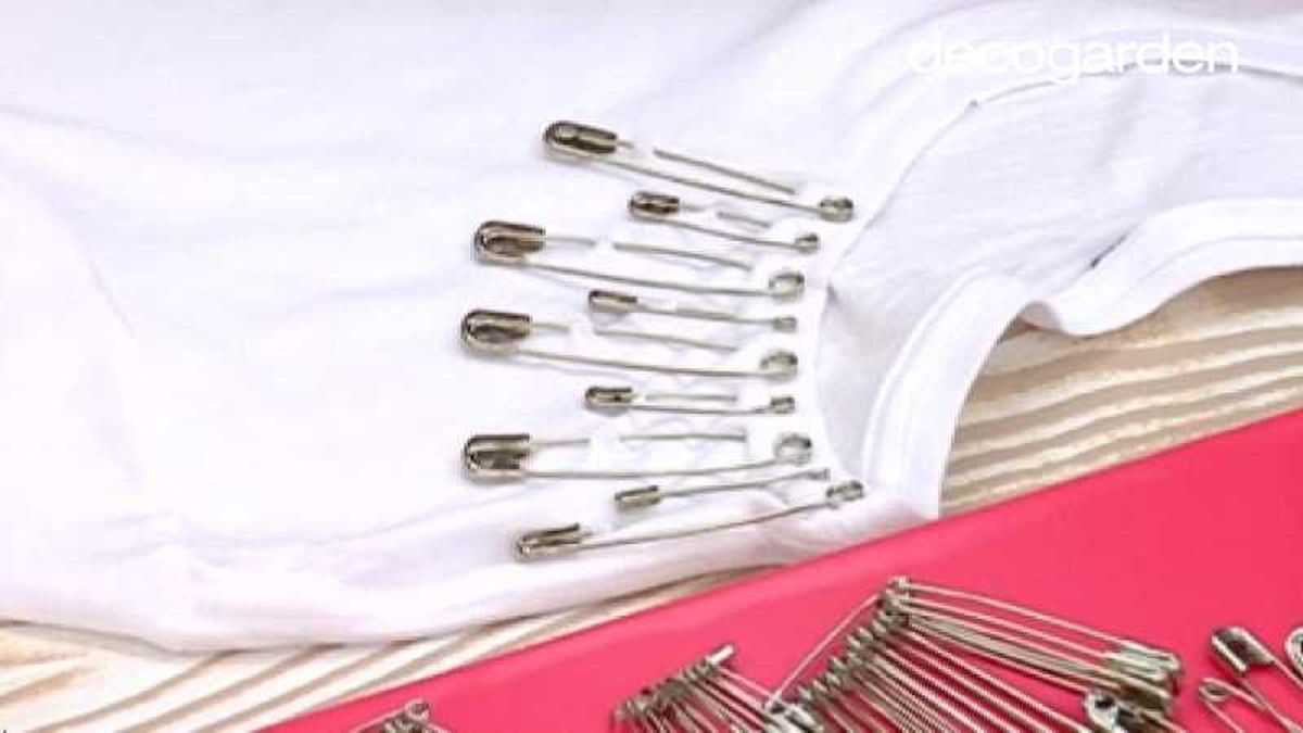 Camiseta decorada con imperdibles de diferentes tamaños.