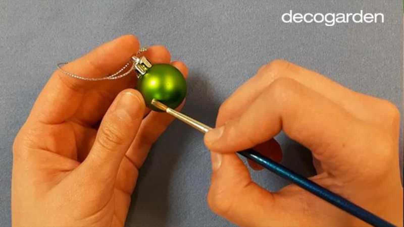 Pintar una bola de Navidad con bola blanca para hacer la huella de la mascota con brillantina.