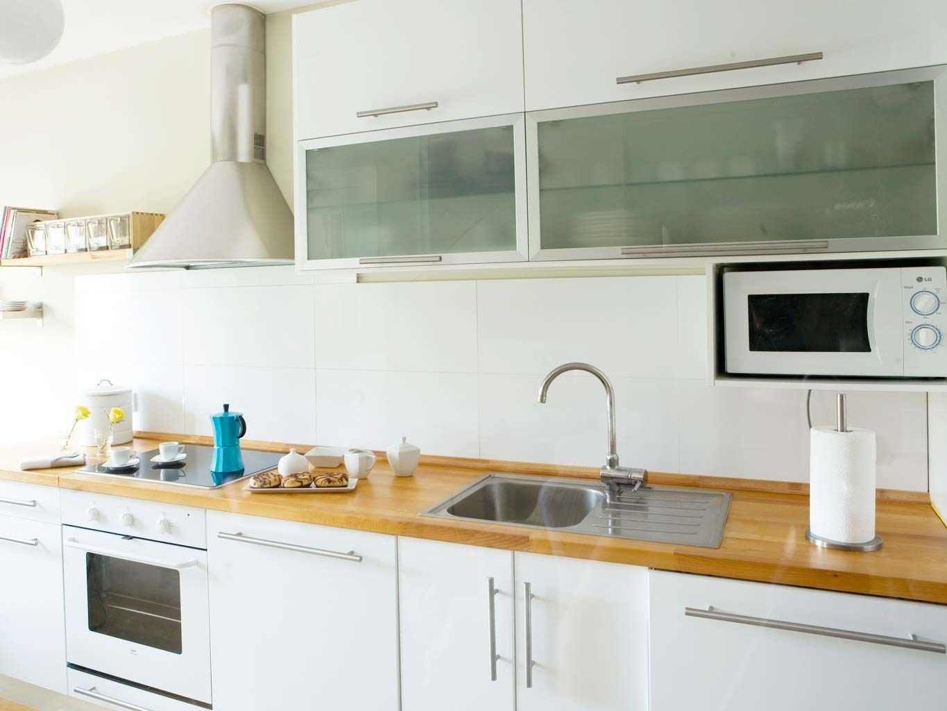 Microondas suspendido debajo de los muebles altos de la cocina.